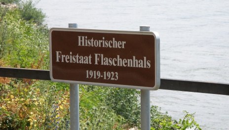 Freistaat Flaschenhals - Hinweisschild am Rheinufer | © Falense via Wikipedia